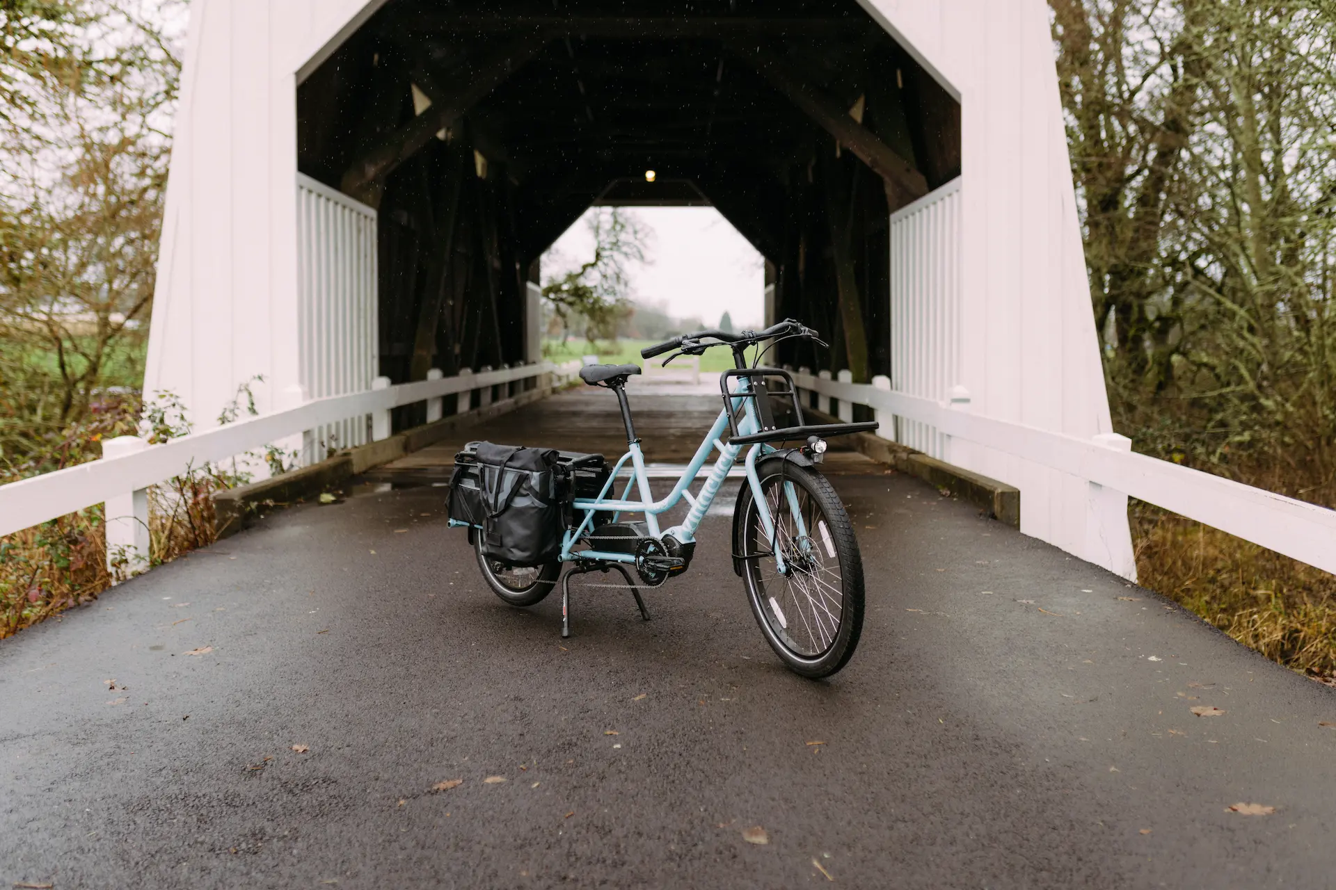 Xtracycle Swoop long-tail electric cargo bike in front of a covered bridge in the country